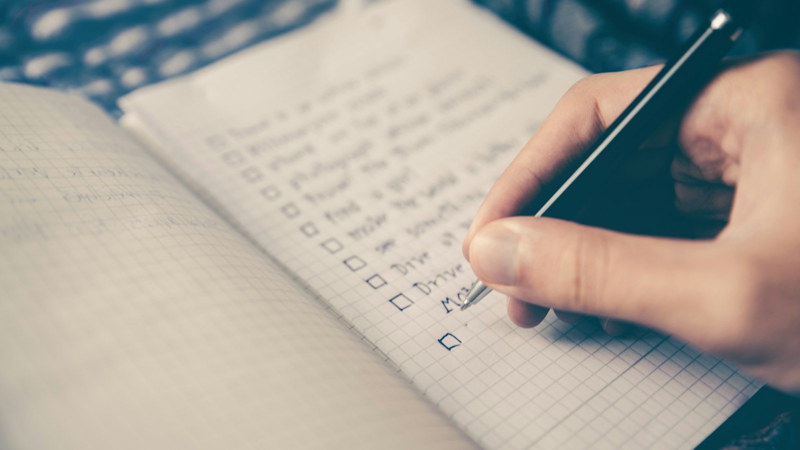 Mão marcando uma lista de tarefas em um caderno